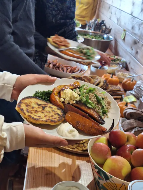 Une assiette garnie tendue au-dessus du buffet : galette, frites de patate douce, salade