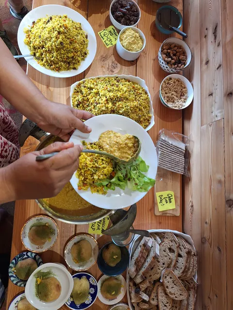 Deux mains remplissent une assiette de riz briani et de salade au buffet