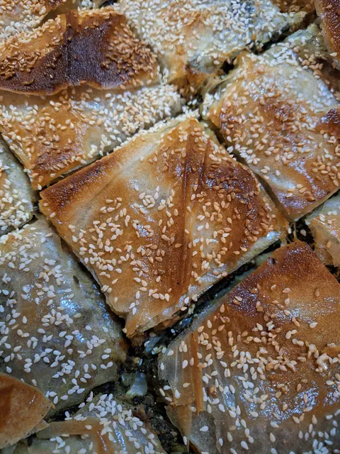 Parts de spanakopita feuilletée et dorée, parsemée de sésame