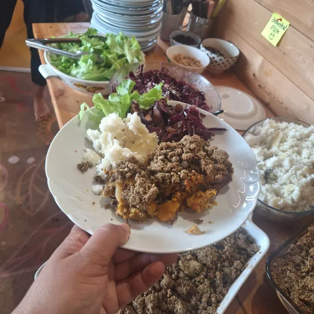 Assiette de crumble salé, purée et chou rouge tenue au-dessus du buffet