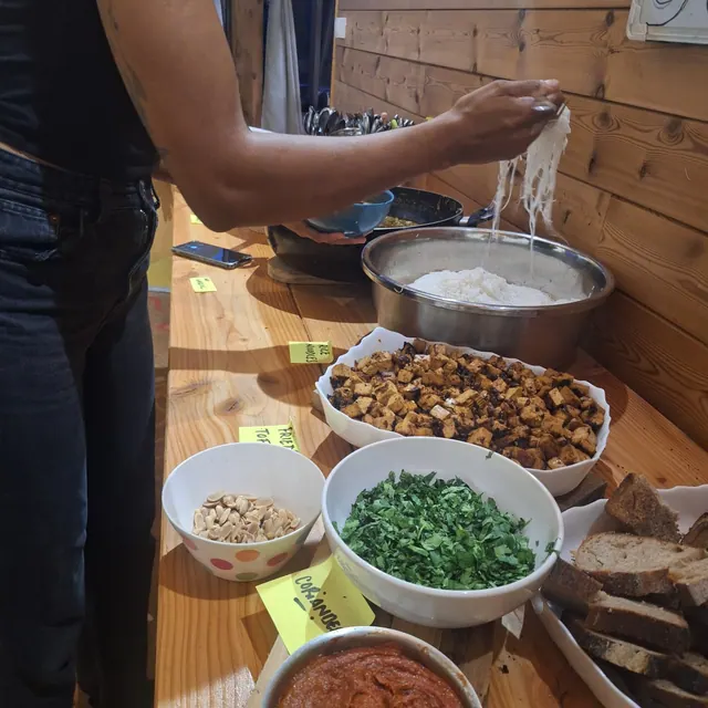 Une personne se sert au buffet du soir : tofu frit, herbes, cacahuètes, pain
