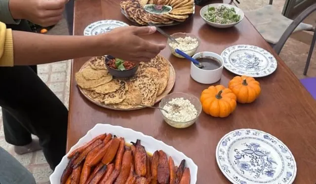 Table garnie de carottes rôties, galettes et petites courges, assiettes à motifs bleus