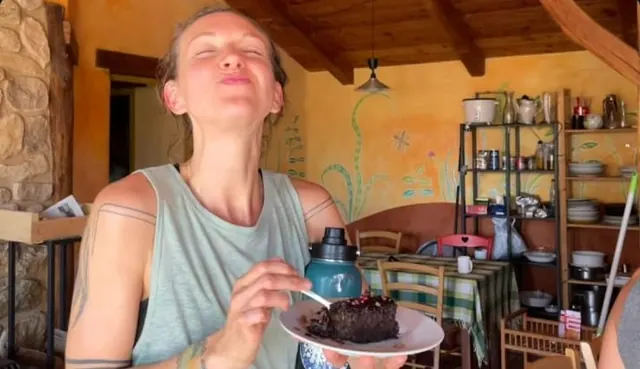 Une personne goûte un dessert au chocolat, yeux fermés, dans une cuisine aux murs orange